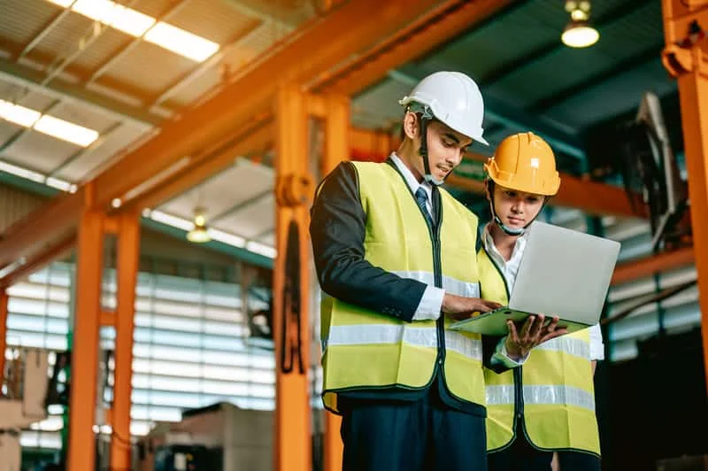 Dos ingenieros conversando sobre detalles técnicos de maquinaria agrícola, analizando planos o especificaciones