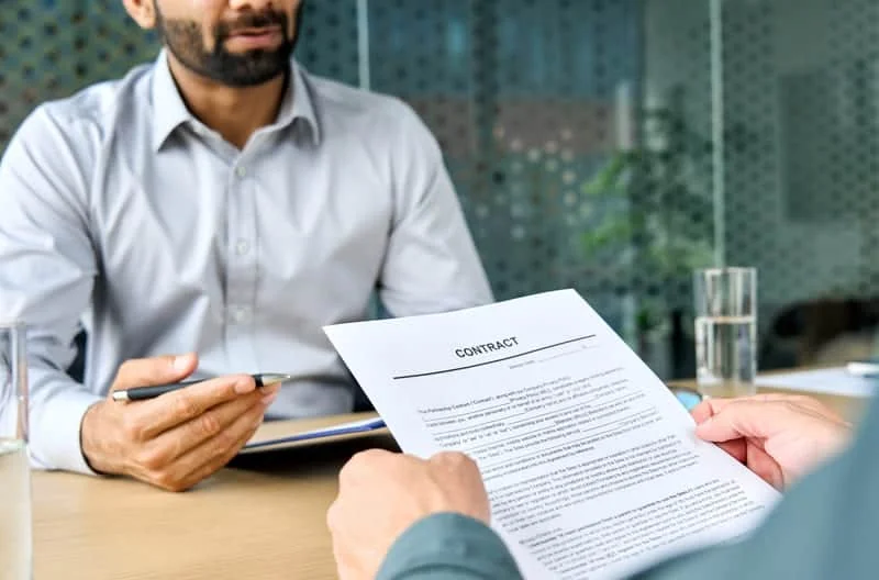 Firma de contrato de compra de tractor entre cliente y representante comercial, formalizando la adquisición
