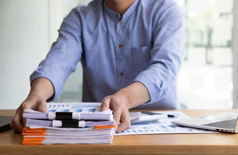 Persona resolviendo documentación de importación, revisando formularios aduaneros y requisitos legales