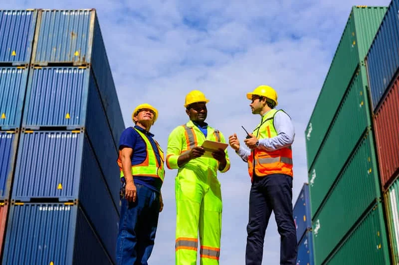 Tres personas conversando sobre problemas logísticos relacionados con la carga y transporte de maquinaria agrícola