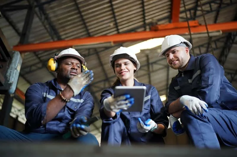 Tres trabajadores conversando sobre procesos operativos o logísticos en un entorno industrial