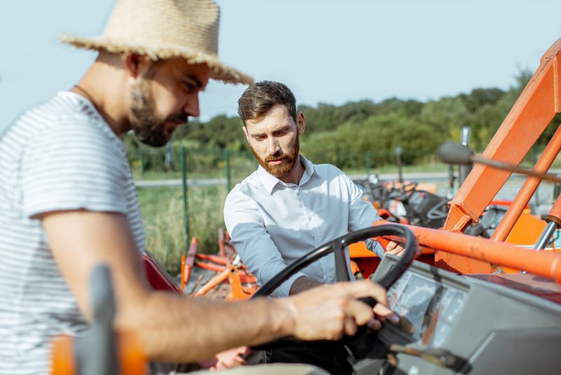 Instructor capacitando a operador de tractor agrícola en campo de entrenamiento práctico