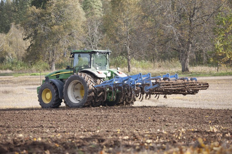 Tractor agrícola acoplado con implementos trabajando en campo de cultivo