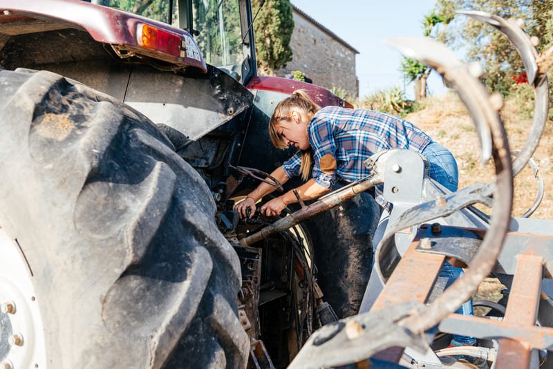 Técnico realizando mantenimiento preventivo a un tractor agrícola en zona rural