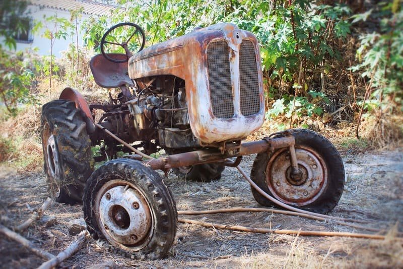 Tractor agrícola antiguo estacionado en campo con señales de desgaste