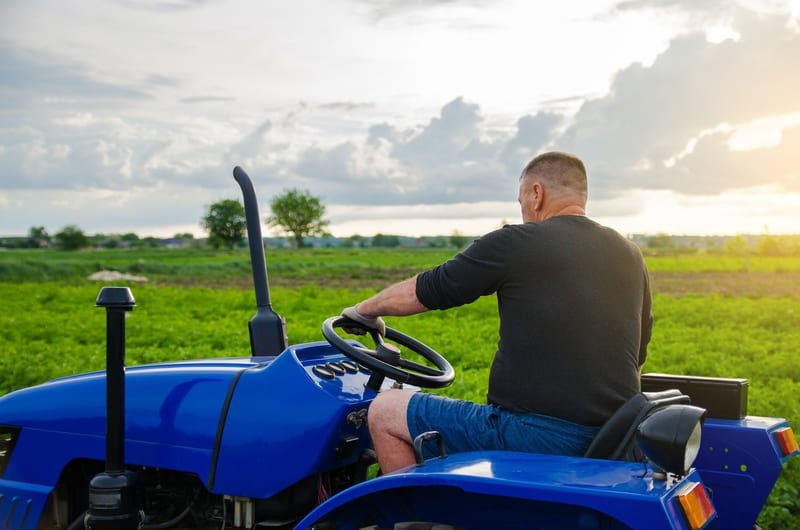 Tractor agrícola compacto operando en espacio reducido con cultivos cercanos