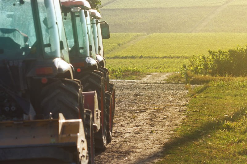 Varios tractores agrícolas trabajando en diferentes tareas dentro de una finca rural