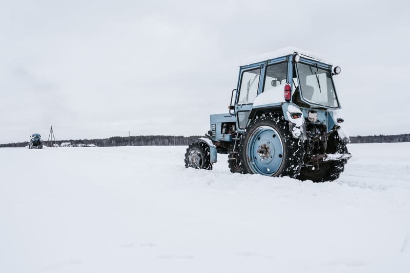 Agricultor evaluando un tractor agrícola en un concesionario durante la temporada de invierno