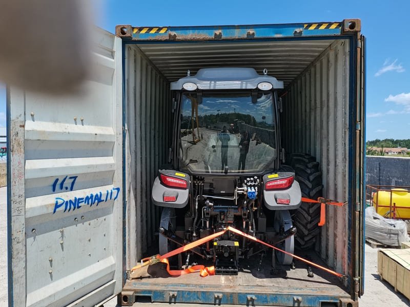 Tractor agrícola siendo cargado en plataforma de transporte para envío nacional o internacional