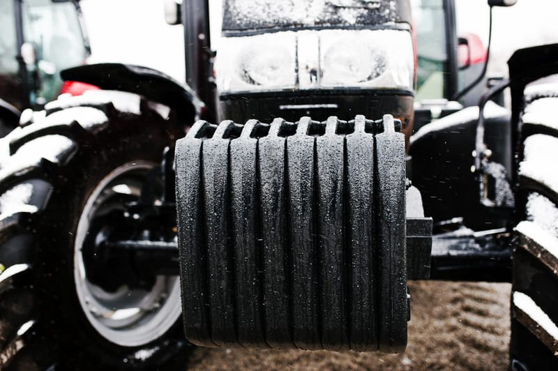 Técnico realizando mantenimiento invernal a un tractor agrícola con nieve en el entorno