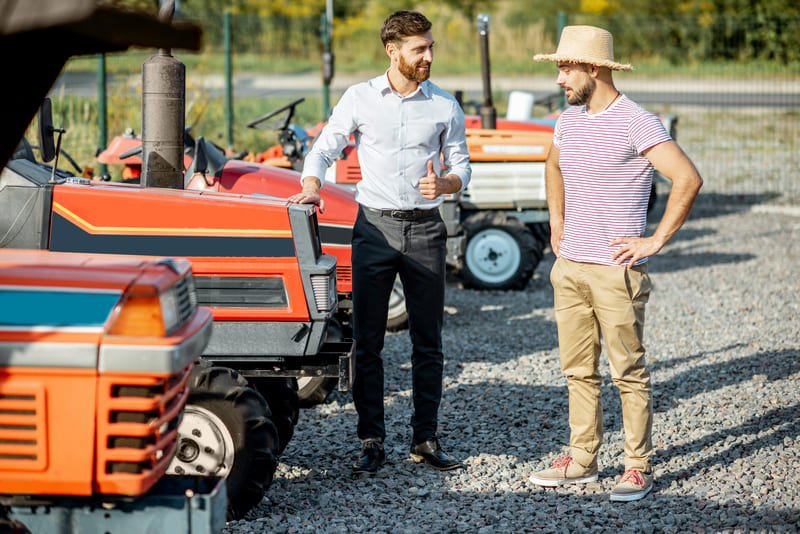 Tractor agrícola usado en exhibición para reventa en lote rural con cartel de “se vende”