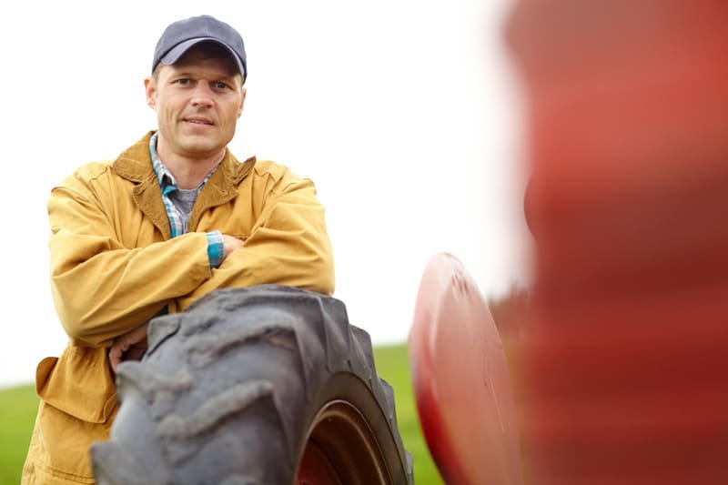 Técnico revisando llantas de tractor para detectar desgaste y daños en zona agrícola.