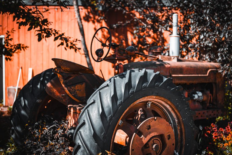 Técnico revisando neumático de tractor durante cambio estacional en campo agrícola.