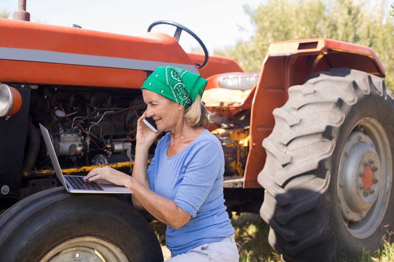 Mujer examinando las llantas de un tractor en una granja, agricultura y mantenimiento seguros.
