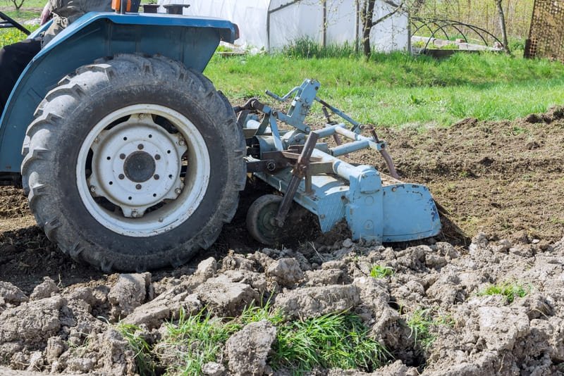 Neumático de tractor soportando terreno rocoso en campo agrícola durante trabajo pesado.