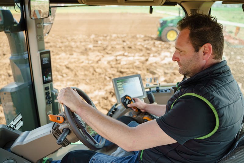 Tractor agrícola moderno equipado con sistema GPS trabajando en campo de cultivo bajo cielo despejado.