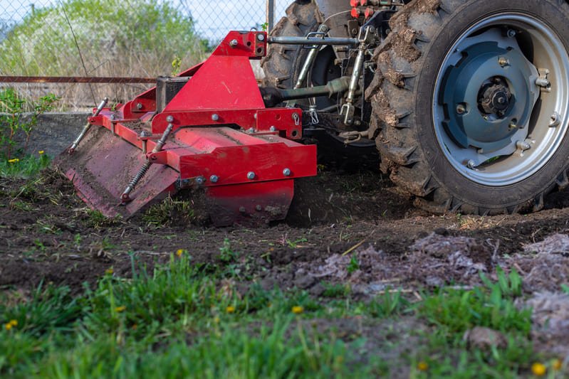 Tractor compacto trabajando con cultivador rotativo en campo agrícola latinoamericano.
