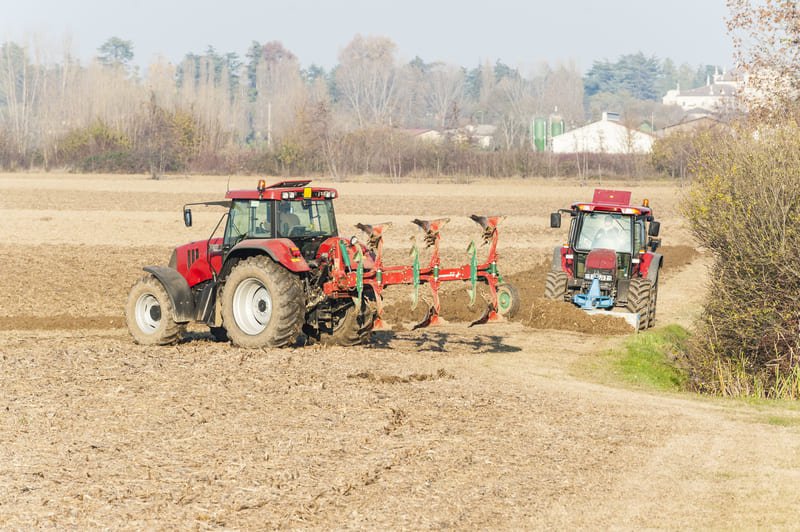 Tractores rojos modernos arando un campo agrícola durante el día bajo cielo despejado