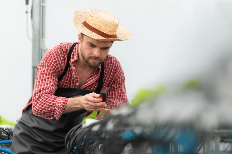 Ingeniero realizando reparación detallada en tractor agrícola al aire libre en campo rural latinoamericano.